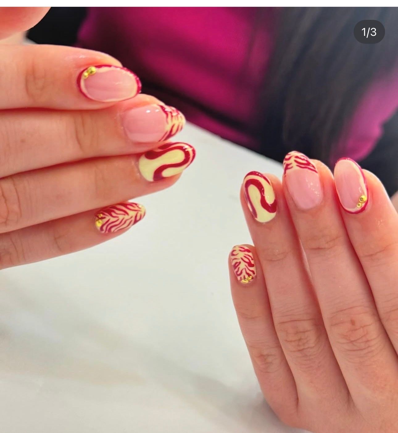 Pink nails with red and yellow swirl art